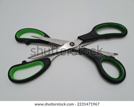 Scissors with green handles, useful for cutting paper or other materials