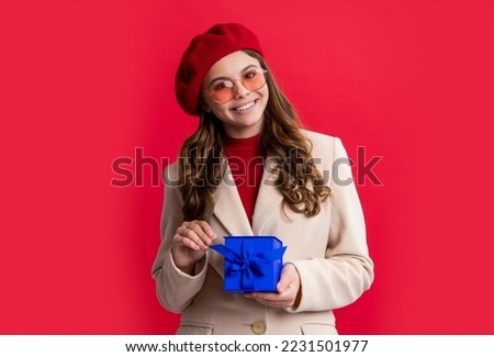 photo of positive stylish teen girl with present. teen girl hold present isolated on red background.