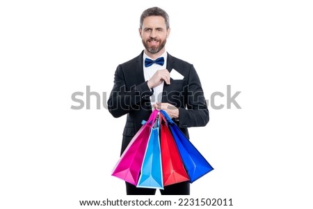 studio shot tuxedo man hold shopping bag and card in pocket. purchase of tuxedo man go shopping