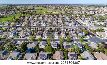 Drone photo over a suburban neighborhood in Brentwood, California with rows of houses with solar panels. 