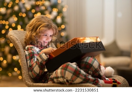 Surprise kid opening Christmas present gift box. Child at home on Christmas. Little kid celebrating Christmas or New Year.