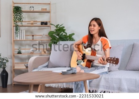 Concept of relaxation with music, Young asian woman singing and playing music with acoustic guitar.