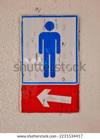 Men's restroom sign with old directional arrows on the wall