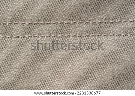 Thread stitching on light denim. Beige jeans fabric background or denim texture. Close up view Royalty-Free Stock Photo #2231538677