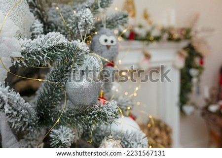 Christmas tree covered with artificial snow and bulbs on decorated fireplace background. Fir tree branches with toys for Happy New Year