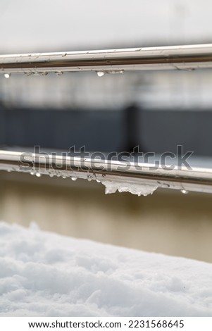 handrail, railing with water drops and wet snow build-up. early spring weather conditions, thaw and snow melting Royalty-Free Stock Photo #2231568645