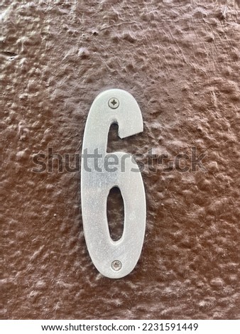 The number 6 on the brown wall of the house, in the center of the frame