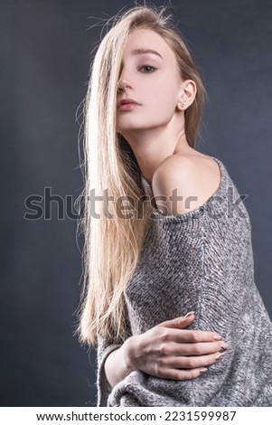 Young beautiful blonde woman in a gray knitted sweater
