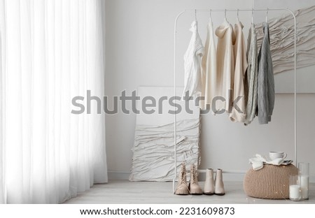 Rack with female sweaters and shoes in room