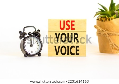 Use your voice symbol. Concept words Use your voice on wooden blocks on a beautiful white table white background. Black alarm clock. Business and use your voice concept. Copy space.