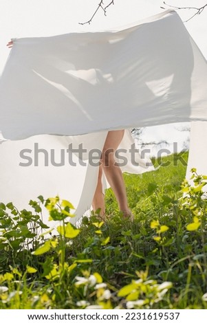 Lady posing with white cloth in meadow scenic photography. Summertime. Picture of woman with green grass on background. High quality wallpaper. Photo concept for ads, travel blog, magazine, article