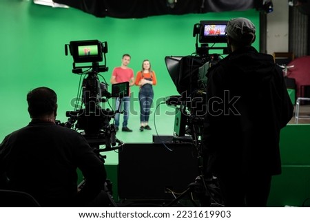 Lights.. Camera.. Action! Woman and Man anchor reporting news in studio. Film and Tv industry.