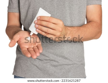 Man applying cream from tube onto hand on white background, closeup