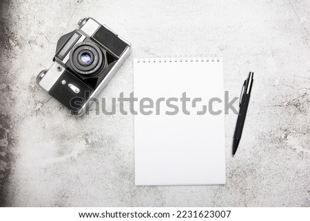 Camera, and accessories on an office concrete table. Top view with copy space. Notebook for sketchbooking. Royalty-Free Stock Photo #2231623007
