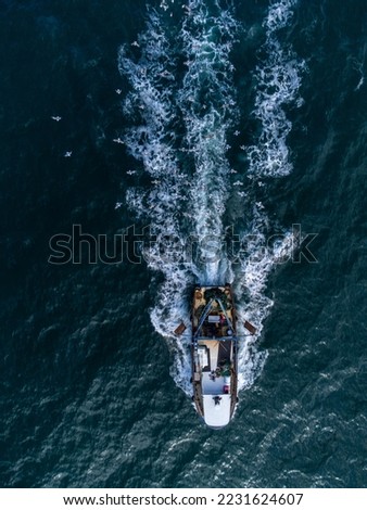 Fishing vessel boat floating in the blue sea, aerial view from drone.