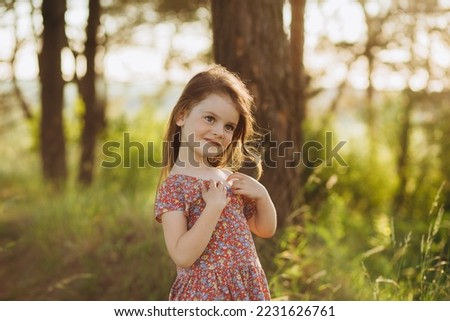 cute little blonde girl in a white dress walking down the path in the forest, the view from the back