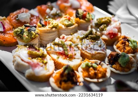 All kinds of appetizers and tapas, sausages, cheeses and vegetables at an event. waiter - selected focus Royalty-Free Stock Photo #2231634119