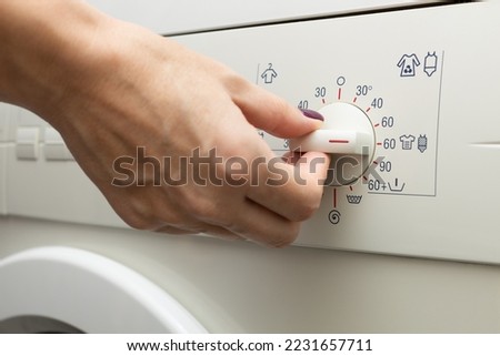 a man chooses a mode on a washing machine. a person chooses a washing mode with a switch. washing mode. temperature mode. 