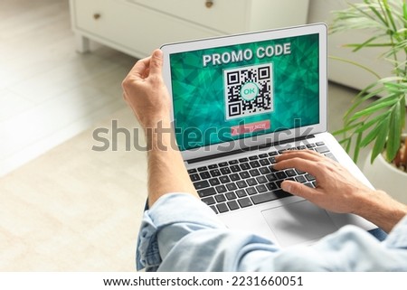 Man holding laptop with activated promo code indoors, closeup