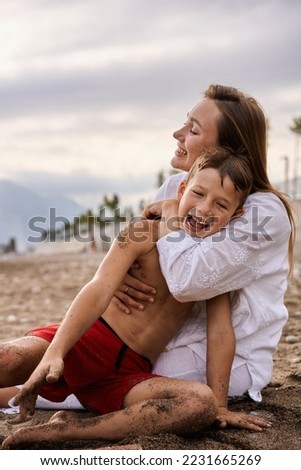 Mom hugs her 6 year old son on the beach. High quality photo