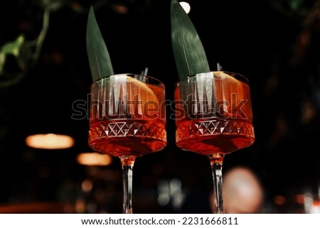 cocktail Aperol spritz in glasses. Cocktail aperol spritz decorated fresh orange slices, ice, greens and two black straw. Typical italian beverage, aperitif made with Prosecco sparkling white wine.