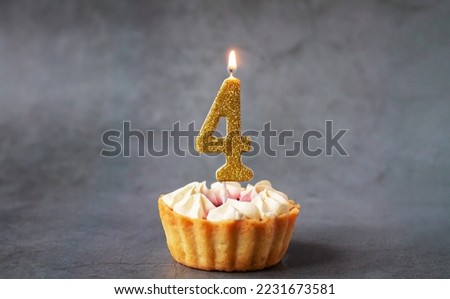 Number four birthday burning candle on tasty cupcake