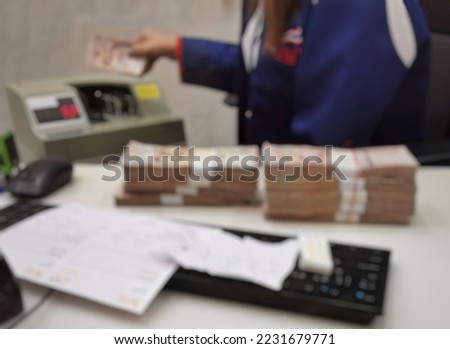 blured​ bank clerk  counting money by money counting machine