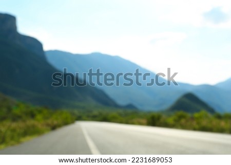 Blurred view of mountains and empty asphalt highway outdoors. Road trip