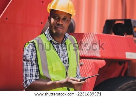 Portrait young African forklift foreman wearing safety vest and hardhat transporting goods in warehouse. Worker driver stacking card boxes by forklift in warehouse store. African American black people