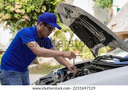 Home service mechanic checking car engine. Car service. Asian man opens his convertible and inspects his car. transportation concept Royalty-Free Stock Photo #2231697129
