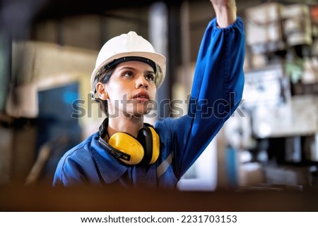 Woman worker in uniform operating machine at factory concentrate on fabrication job on drill