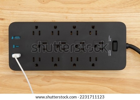 Black surge and ground protector with USB protection on wood desk Royalty-Free Stock Photo #2231711123