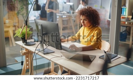 Creative Multiethnic Female Working on Computer with Two Displays in an Office. Happy Project Manager Browsing Internet, Writing Tasks, Developing a Marketing Strategy for a Corporate Partner.