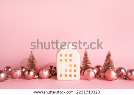 Christmas and New Year miniature house with decorations on pink background. Copy space for text. Winter card. Holiday and celebration concept