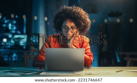 Portrait of a Happy Successful Businesswoman Using Laptop Computer in Creative Agency in the Evening. Black Female Smiling while Browsing Internet, Checking Funny Memes on Social Media Network. Royalty-Free Stock Photo #2231746647