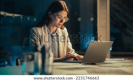 Stylish Female Working on Laptop Computer in a Company Office in the Evening. Young Project Manager Browsing Internet, Writing Tasks, Developing a Marketing Strategy for a Financial Institution. Royalty-Free Stock Photo #2231746663