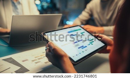 Multicultural Creative Colleagues Discussing a New Business Opportunity, Talking in an Office Meeting Room. Close Up of a Tablet Computer with Project Planning and Development Timeline. Royalty-Free Stock Photo #2231746801