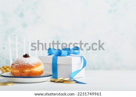 Happy Hanukkah. Hanukkah sweet doughnuts, gift boxes, white candles and chocolate coins on white wooden background. Image and concept of jewish holiday Hanukkah. Top view.