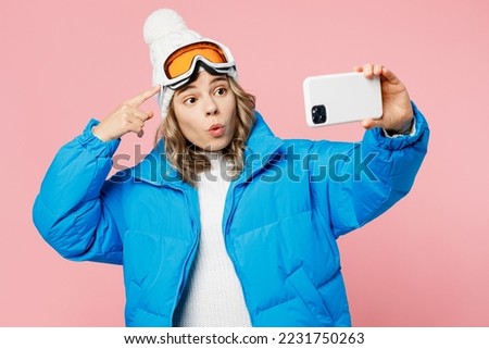 Snowboarder woman wear blue suit hat ski jacket do selfie shot on mobile cell phone show goggles mask isolated on plain pastel pink background. Winter extreme sport hobby weekend trip relax concept