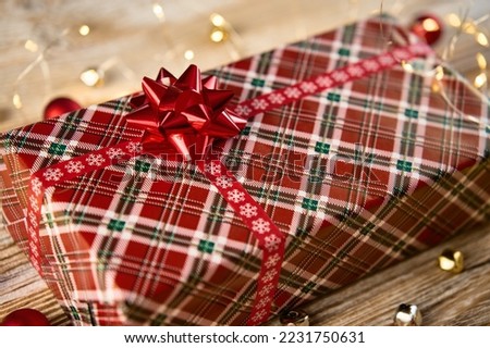 Above view of festive gift box with festive ribbons and bow. Present for Christmas holidays on wooden background with bokeh lights