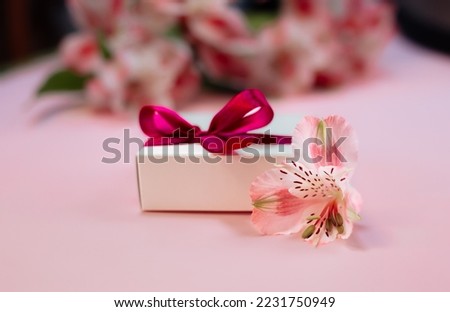 bouquet of red alstroemeria flowers. pink background . Flower card and gift box with ribbon close up. 