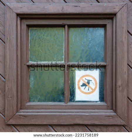 Sign "Dogs are forbidden to pee" by private dog haters. Old wooden door with rectangular windows