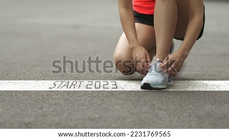 happy new year 2023,2023 symbolizes the start of the new year. Start with a woman preparing to run on the road engraved with the year 2023. The goal of Success. Getting ready for the new year Royalty-Free Stock Photo #2231769565