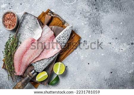 Raw Gilthead Sea bream fish fillets on a butcher cutting board. Gray background. Top view. Copy space. Royalty-Free Stock Photo #2231781059