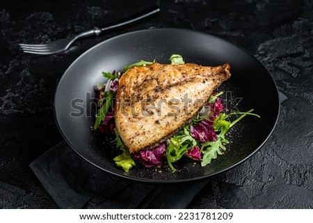 Grilled Sea Bream Dorado fillets served on fresh salad. Black background. Top view. Royalty-Free Stock Photo #2231781209