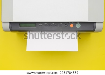 Top view of a black printer and a blank sheet of a4 paper on a yellow background, layout.Office Equipment, close-up.Copy space.Multifunction device. Multifunction printer.