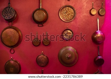 part of the decor and the material from which it is made;
copper dishes hang on a red wall