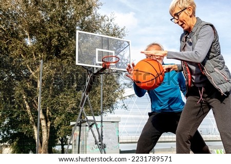 Mature couple play basket ball on playground