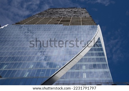 glass and metal building under construction on Front St in downtown Toronto with angled metal triangular shape on side of building glass windows half way up upper part still under construction 