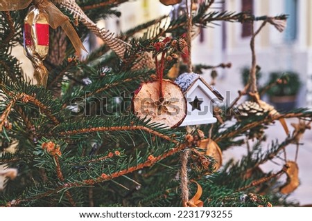 Decorating Christmas tree with dried piece apple, toy house. Natural Xmas ornaments for Christmas tree, zero waste, soft focus